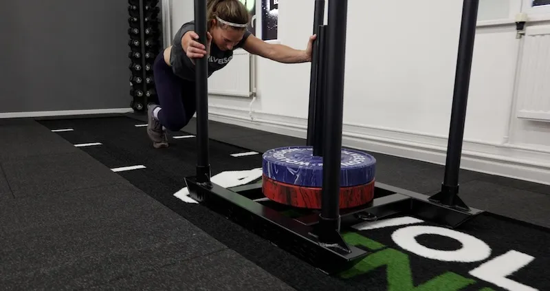 Weighted sled push on gym turf