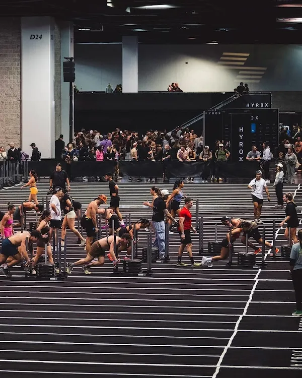 Wide view of athletes preparing weighted sleds across multiple indoor lanes.