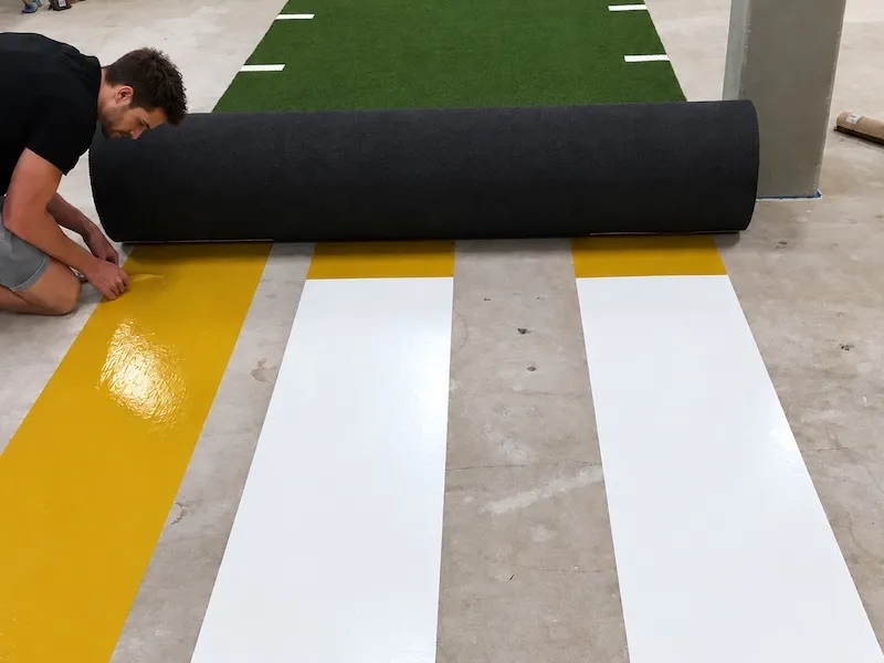 Temporary turf installation using double-sided tape on a training floor.