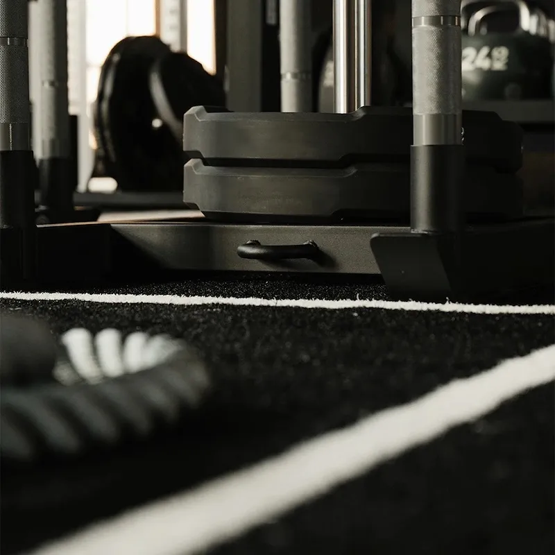 Weighted training sled on a green turf lane in a commercial gym.
